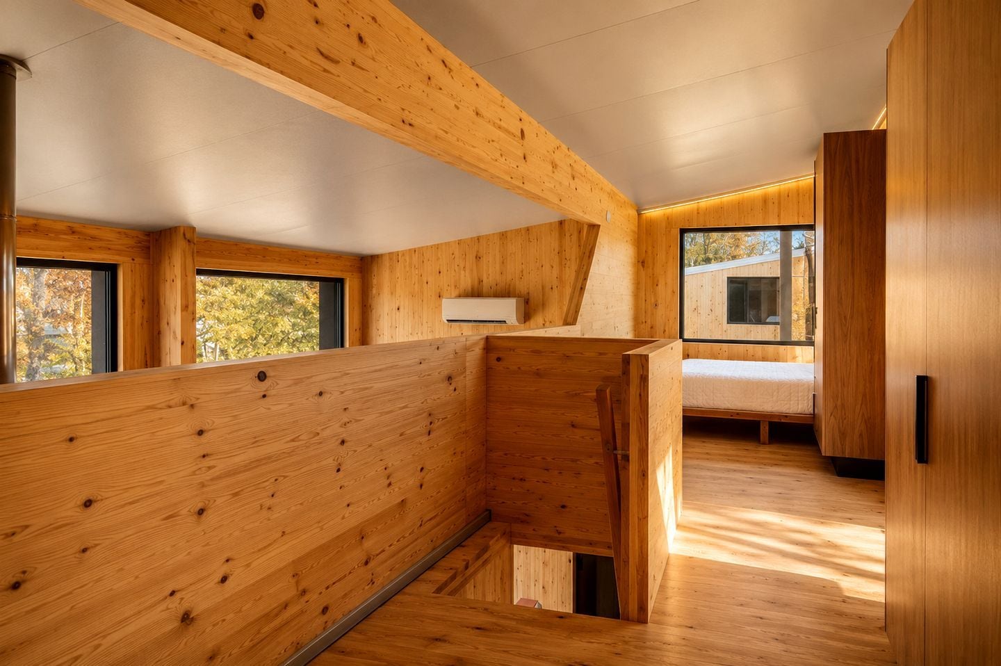 Un interior moderno con paneles de madera, una cama y una ventana con vistas a árboles.