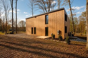 A modern wooden cabin with a flat roof, a large window, and a door. - Contemporary Forest Hideaway with Stunning Glass Architecture in Tracy, Tennessee (Tracy City)