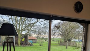 A room with a large sliding glass door leading to a backyard. - Le Fournil, a quiet one-room studio near the beaches (Courtils)