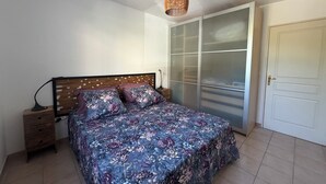 Een slaapkamer met een bed, een nachtkastje, een kledingkast en een deur.
