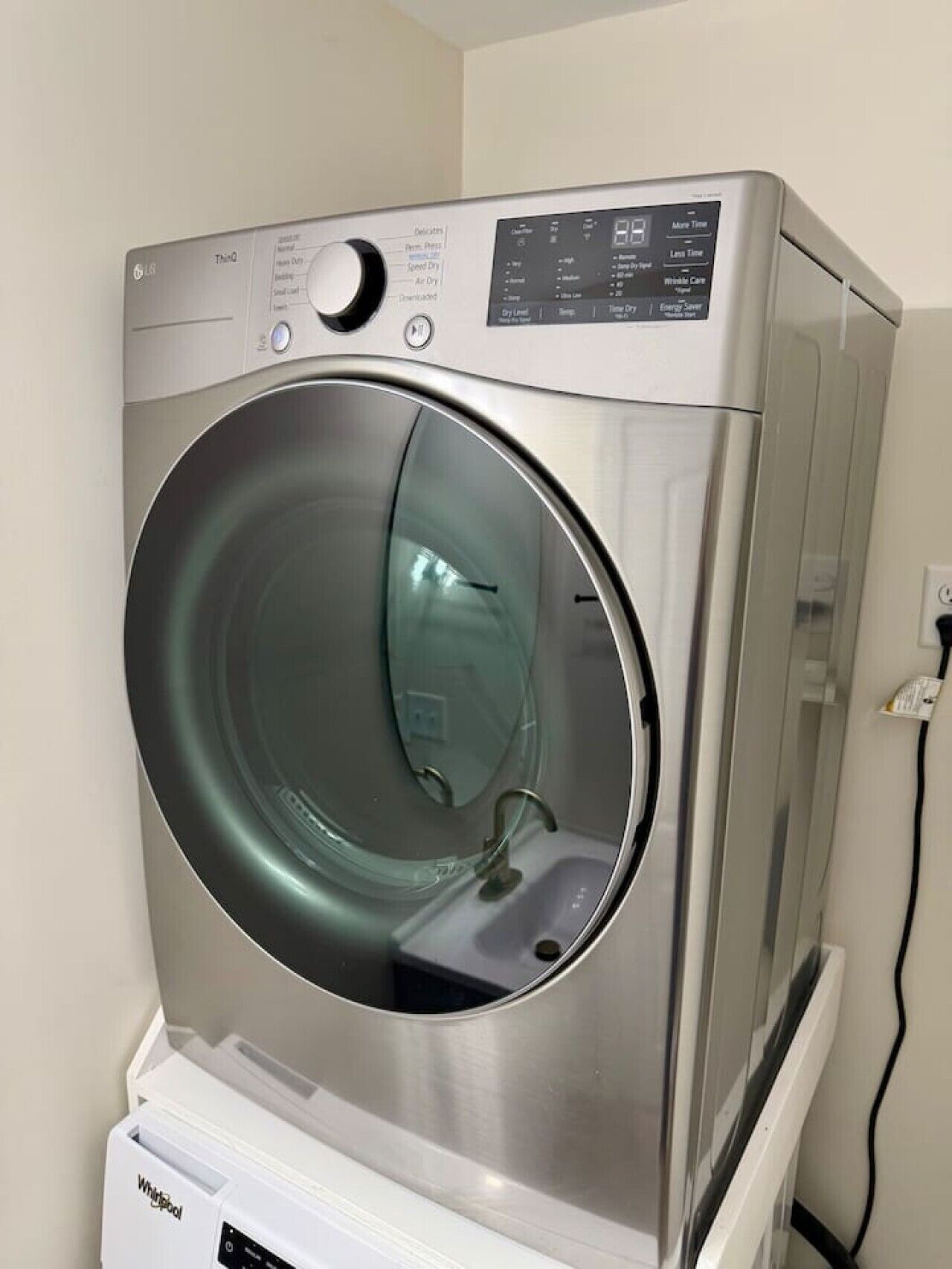 A front-loading LG washer with a control panel, a stainless steel finish, and a Whirlpool brand dryer below.