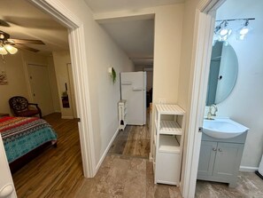 A bedroom with a bed, a dresser, a mirror, and a door leading to a hallway. - Charming Beaufort Space | Perfect 4 Extended Stays (Beaufort)