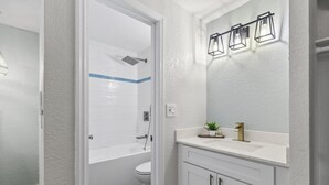 Une salle de bain avec une baignoire blanche, des toilettes et un lavabo avec un miroir au-dessus.