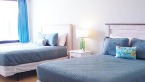 Camera d'albergo con due letti, un comodino, una lampada e una finestra con tende.