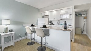 Una cucina moderna con mobili bianchi, un'isola centrale con sgabelli da bar, un forno a microonde e una macchina da caffè.