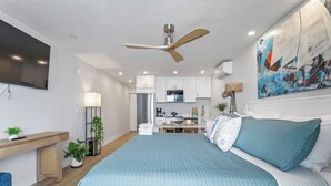 Una habitación de hotel moderna con una cama grande, un escritorio, una kitchenette y un ventilador de techo.