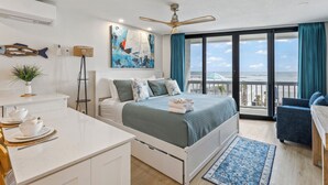 Un dormitorio moderno con cama, escritorio, silla, balcón con vistas y ventilador de techo.