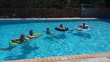 Ein Schwimmbecken mit klarem, blauem Wasser, umgeben von einem Holenzaun und einer Steinmauer.