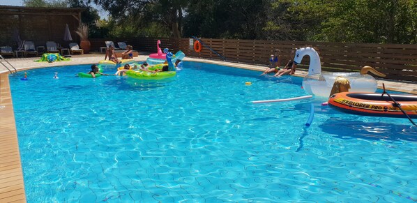 A swimming pool with inflatable toys and lounge chairs. - 2BR Family Apartment in Gouvia – Apt 2 (Kontokali)
