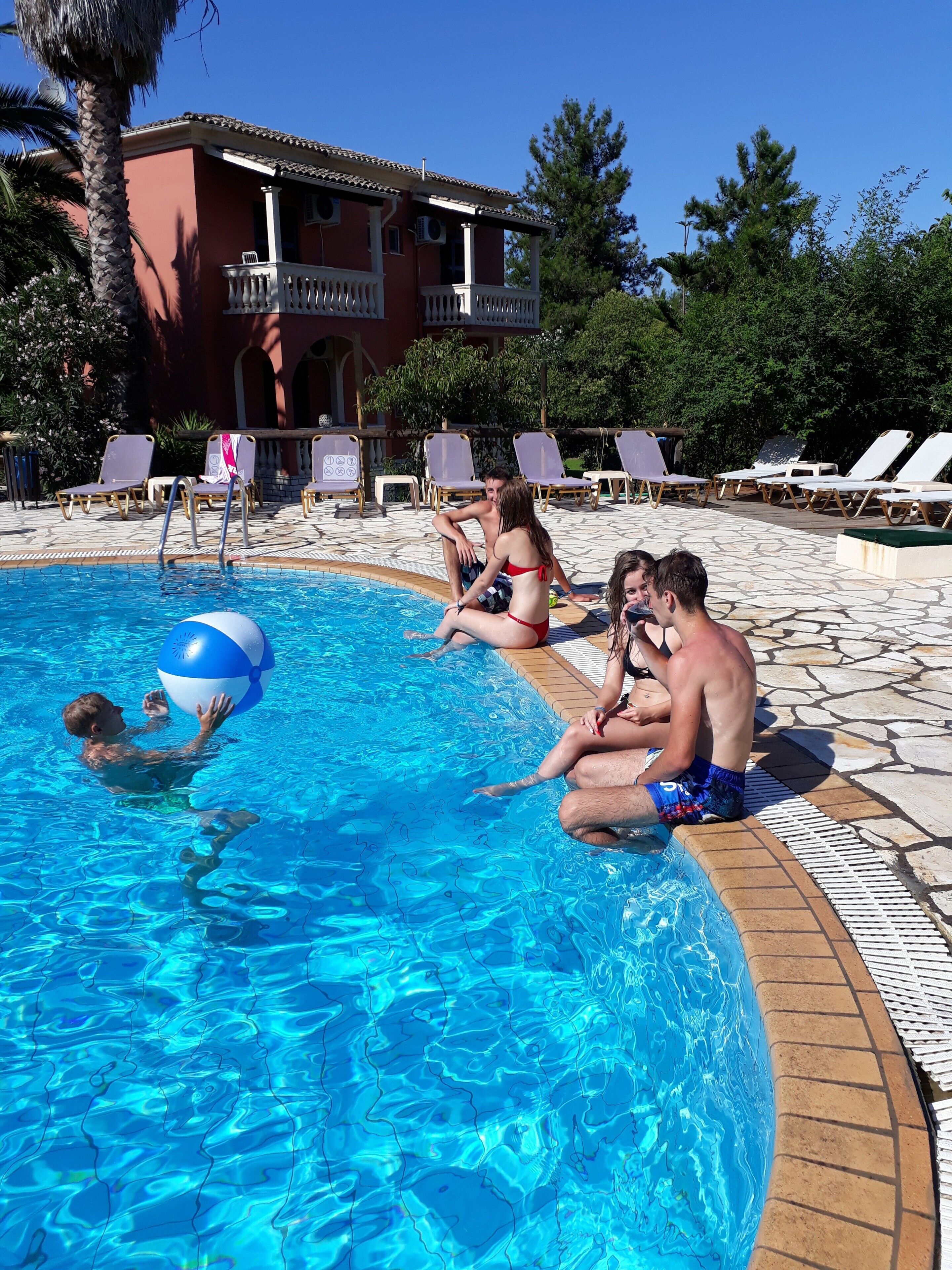 Une piscine avec des chaises longues et un bâtiment en arrière-plan.