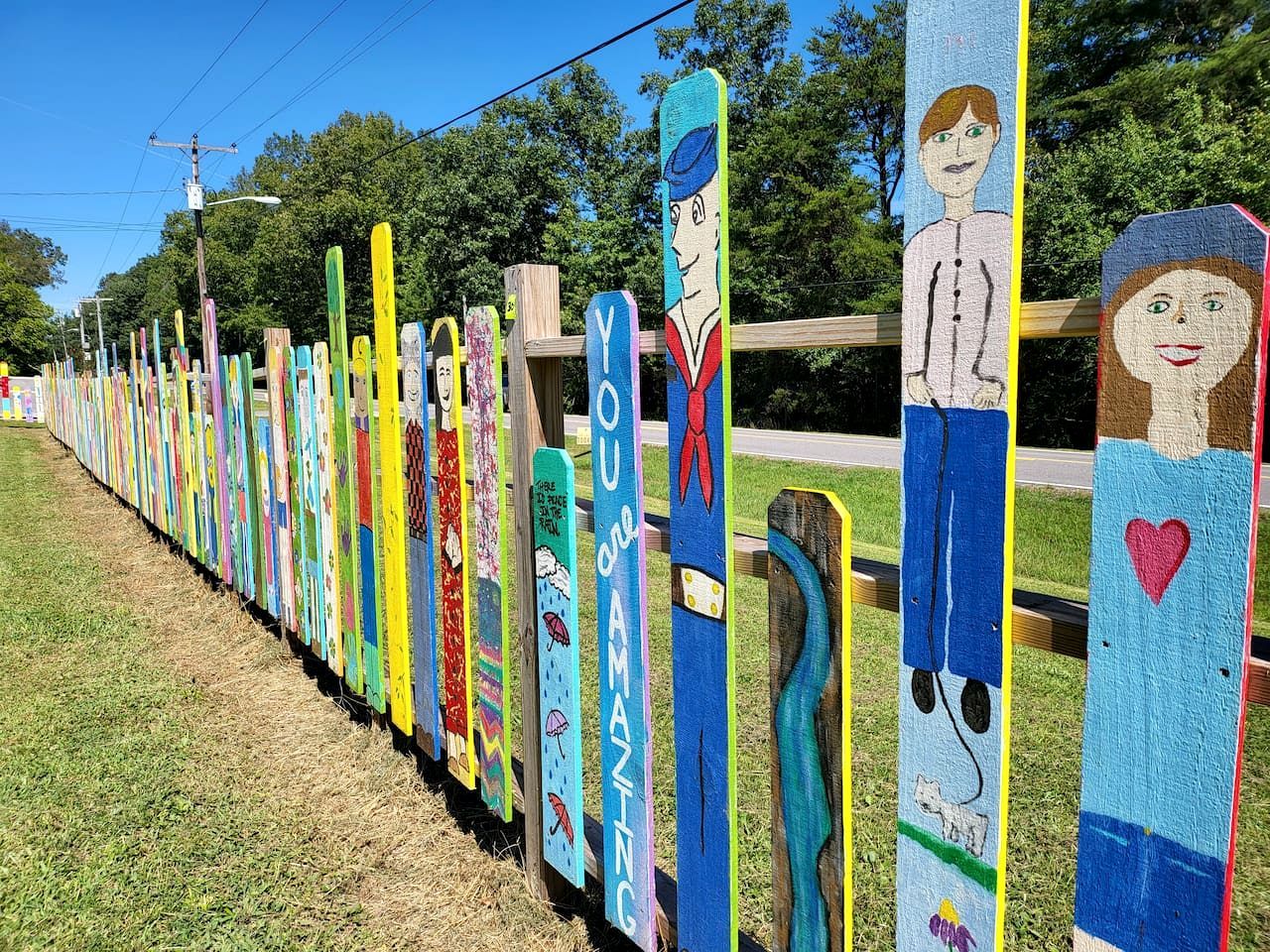 A row of colorful painted wooden posts with various figures and text.