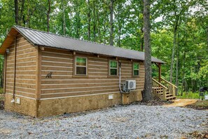 Une cabane en rondins avec un toit en métal, un petit porche et un appareil de climatisation.