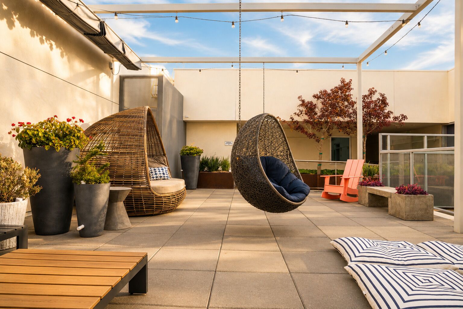 An outdoor patio with hanging chairs, a wooden bench, and potted plants.