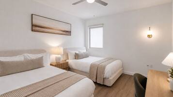 Une chambre d’hôtel avec deux lits, un ventilateur de plafond, une fenêtre et une table de chevet avec une lampe.