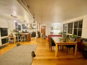 A spacious living area with a kitchen, dining table, and a cozy seating area. - Funky house close to Castlemaine, surrounded by extensive gardens and bushland. (Golden Point)