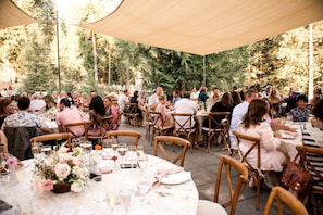 An outdoor dining area with round tables, chairs, and a canopy. - Boutique Glamping Retreat with Elevated Views and Serenity in Sandpoint, Idaho (Sandpoint)