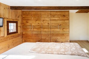 Una camera da letto con pareti in legno, un letto con biancheria a motivi e un ampio guardaroba.