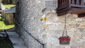 Um edifício de pedra com uma escadaria de pedra, um cesto de flores pendurado e uma placa amarela com uma seta preta.