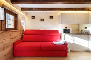 Ein rotes Sofa in einem Raum mit Holzwänden und einer Küchenzeile.