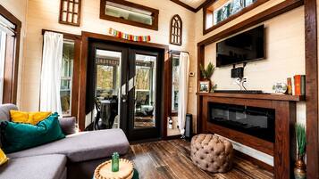 Een gezellige woonkamer met een open haard, een televisie en een eethoek met een tafel en stoelen.