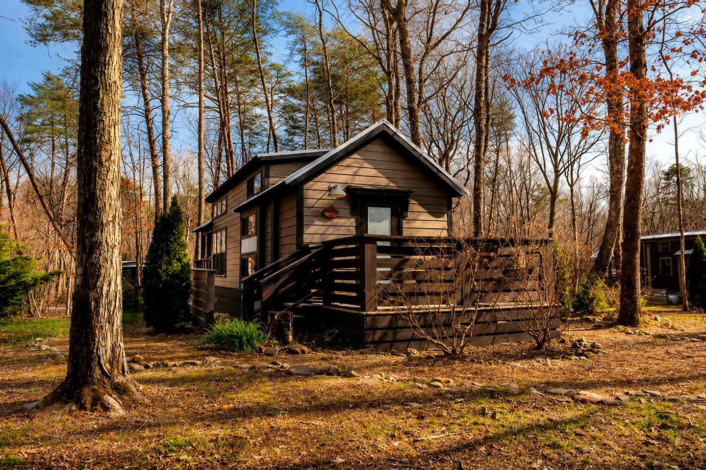 A cabin with a wooden exterior, a front porch, and a staircase leading to the entrance.