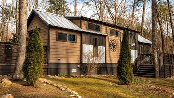 A cabin with a metal roof, wooden siding, and a compass symbol on the wall.