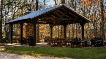 A covered pavilion with seating, surrounded by trees and a gravel path.
