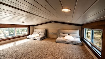 A bedroom with two beds, a wooden ceiling, and a carpeted floor.