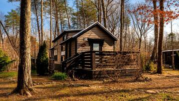A cabin with a wooden exterior, a front porch, and a staircase leading to the entrance.