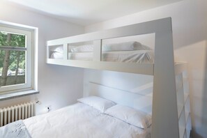 A bunk bed with a white headboard and a window with a view of trees. - Maison Rue de La Neige - Family Escape (Valtournanche Aosta)