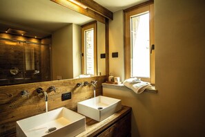 Ein Badezimmer mit zwei Waschbecken, einem Holz-Waschtisch, einem großen Spiegel und einer Duschkabine.