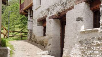 A rustic stone building with wooden balconies and a narrow pathway leading to a door.