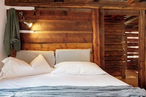 L’intérieur d’un chalet en bois, avec un lit, des oreillers, une serviette suspendue et un plafond en bois.