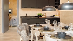 Una cucina moderna con mobili scuri, un tavolo da pranzo imbandito per sei persone e un'ampia lampada a sospensione.