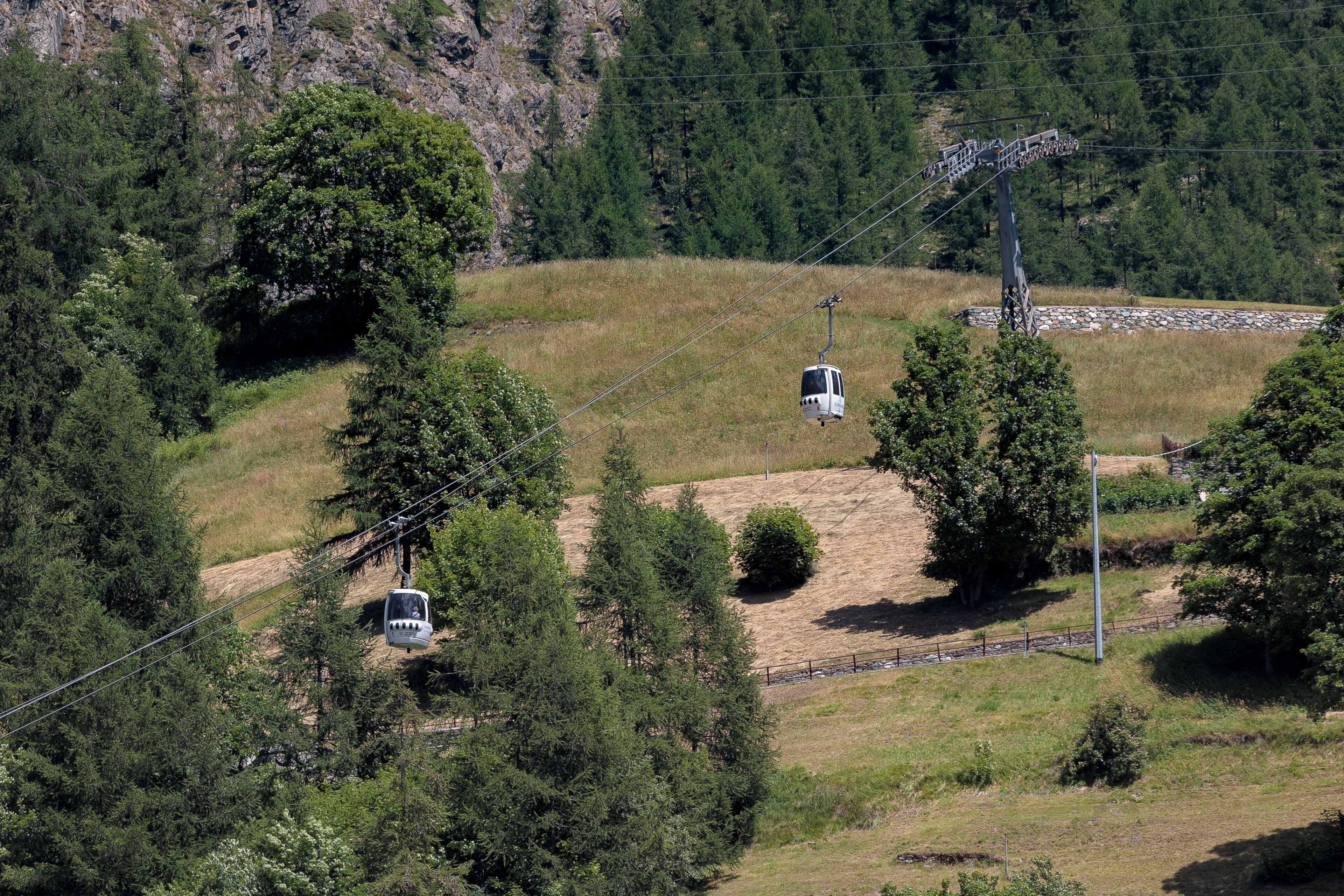Un sistema de teleférico en una zona montañosa con vegetación y terreno rocoso.