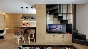 A modern living room with a flat-screen TV, wooden flooring, a cowhide rug, and a staircase. - Pandora Mountain View - Central Apartment (Breuil-Cervinia)