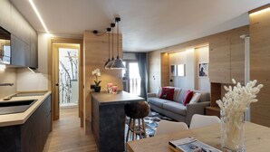 A modern kitchen with a central island, a dining area with a table and chairs, a sofa, and a large window. - Pandora Mountain View - Central Apartment (Breuil-Cervinia)