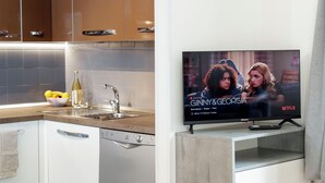 A modern kitchen with a built-in dishwasher, a sink, and a countertop with a bowl of fruit and a bottle of wine.