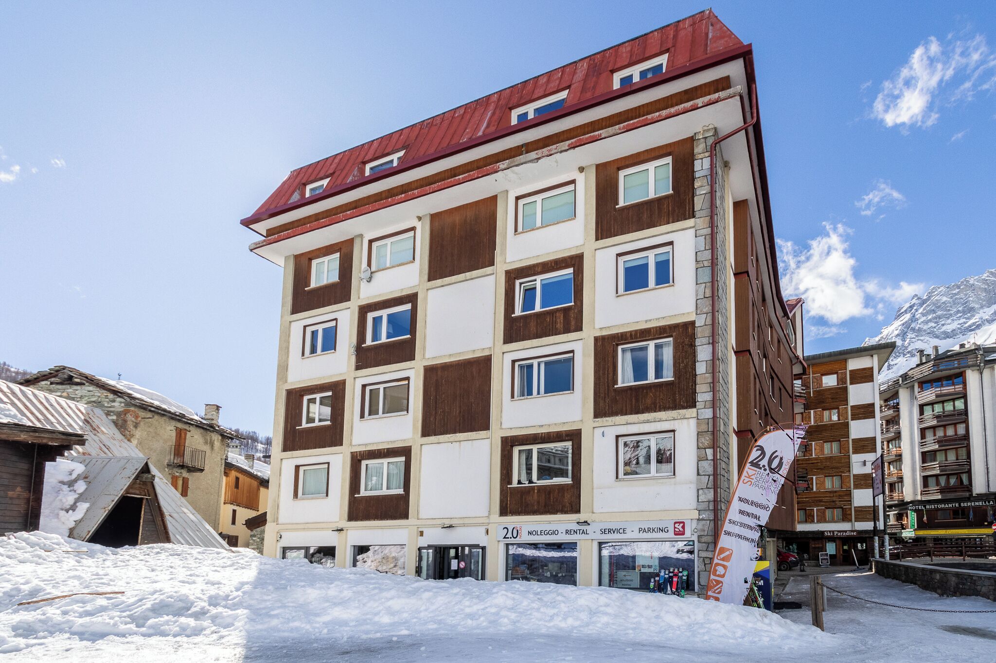 A multi-story hotel with a red roof, multiple windows, and a sign indicating rental services.