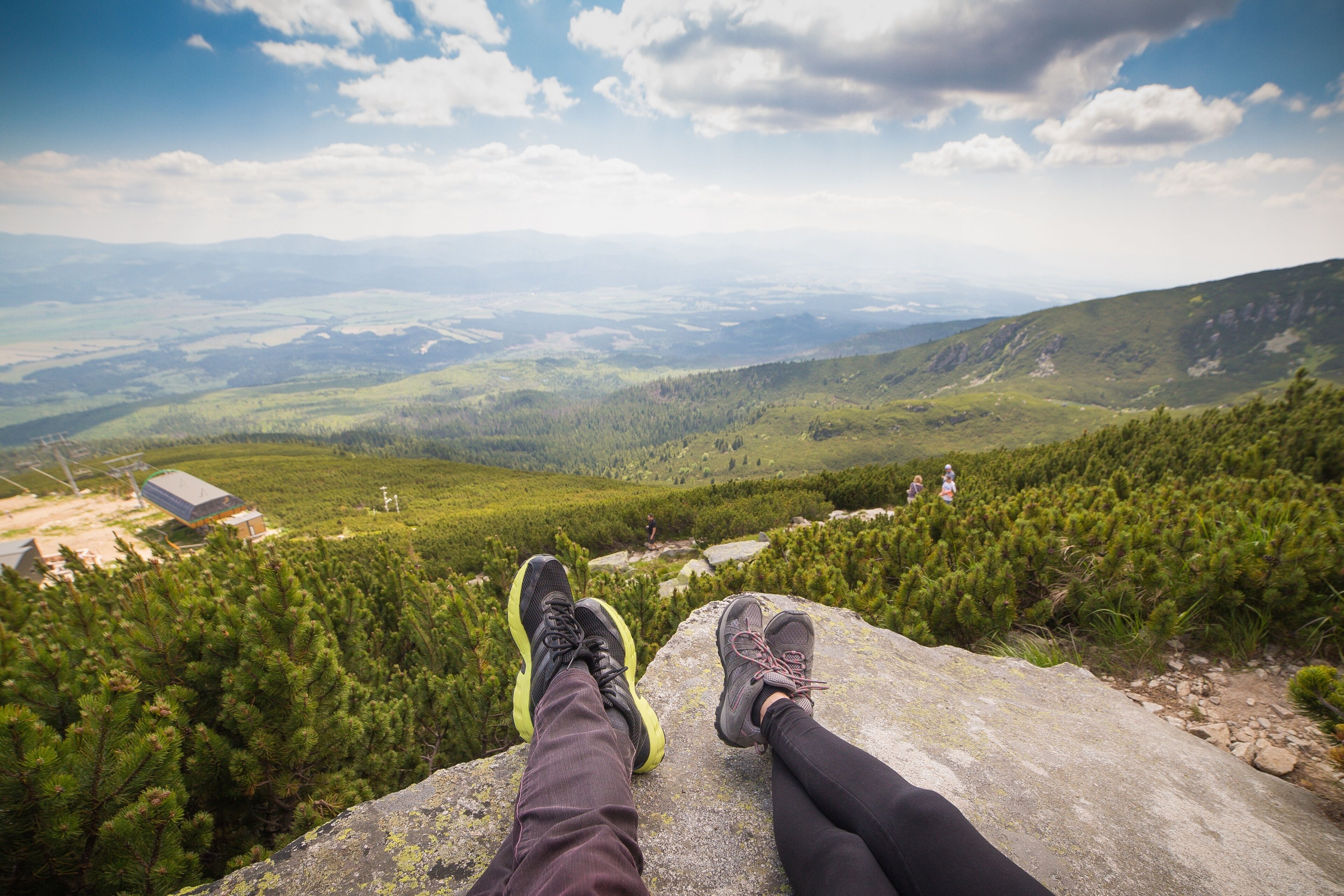 A person sitting on a rock with a view of a mountainous landscape.