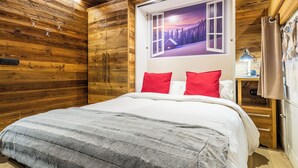 Una habitación con paneles de madera, una cama, una mesita de noche, una lámpara y una ventana con vistas panorámicas.