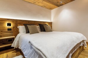 Ein Schlafzimmer mit einem hölzernen Kopfende, einer weißen Bettdecke und gemusterten Kissen.