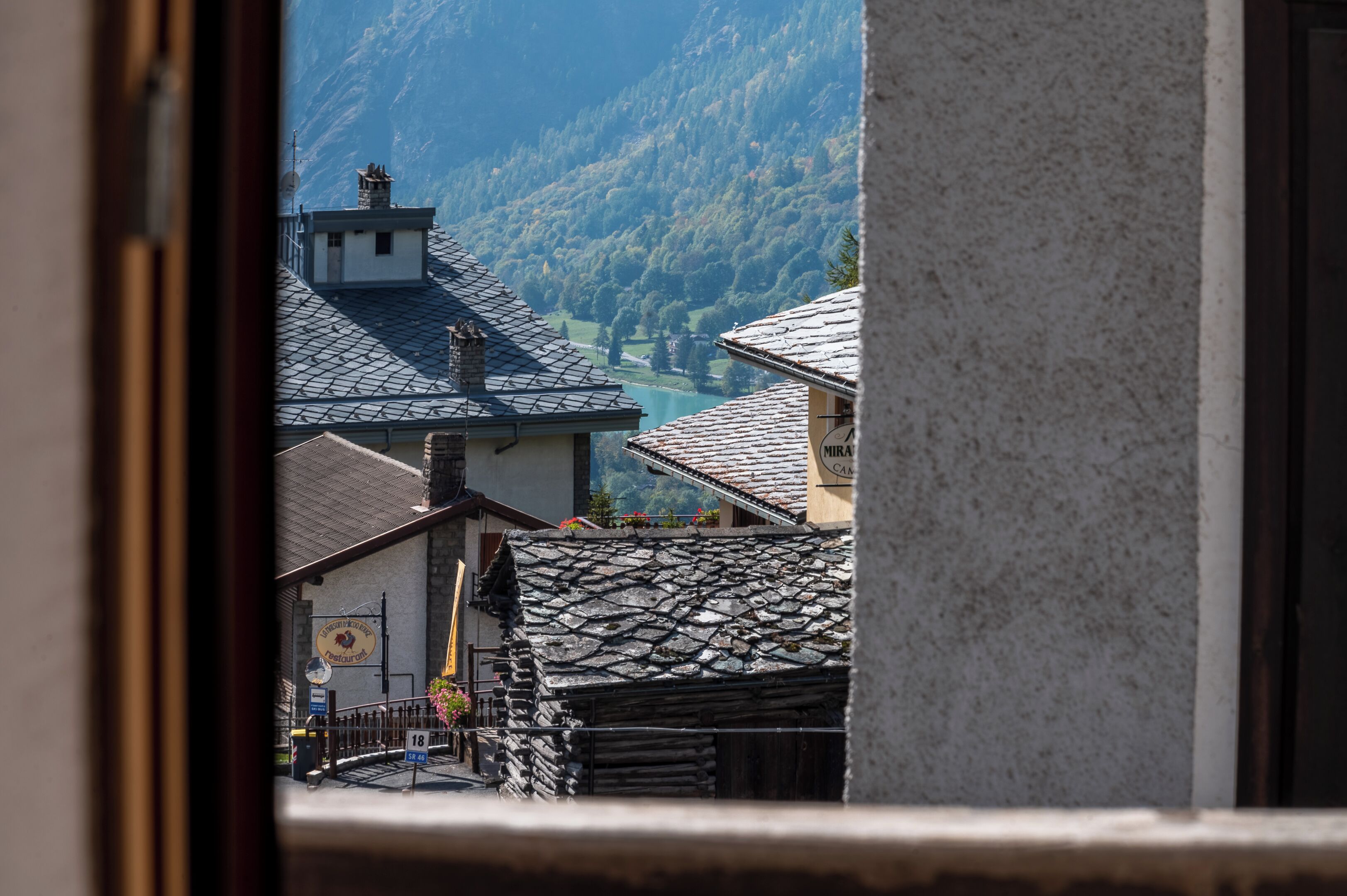 Un pueblo de montaña con arquitectura tradicional, un restaurante visible y una vista despejada de las montañas circundantes.