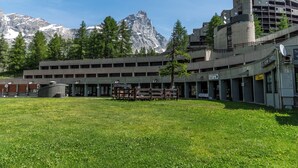 Un bâtiment doté d’une cour intérieure, entouré d’arbres et ayant une chaîne de montagnes en toile de fond.