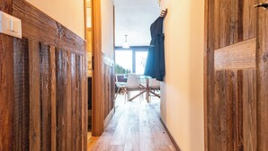 Un pasillo con paneles de madera, una mesa con sillas y vistas al exterior a través de una ventana.