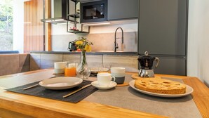 Uma mesa de madeira com uma cafeteira, um prato de biscoitos e um vaso de flores.