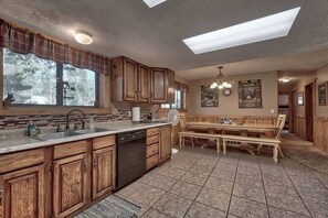 Une cuisine dotée de meubles en bois, d’un lave-vaisselle, d’un grand îlot central et d’un coin repas avec des bancs.