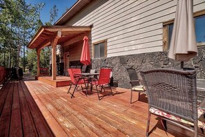 A wooden deck with outdoor furniture, a stone wall, and a covered patio area. - Incredible Cabin Perfect for Family Reunions near Yellowstone, Idaho (Island Park)
