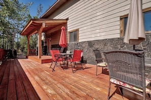 A wooden deck with outdoor furniture, a stone wall, and a covered patio area.