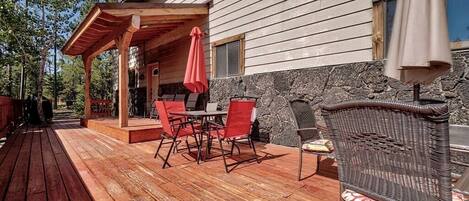 A wooden deck with outdoor furniture, a stone wall, and a covered patio area.